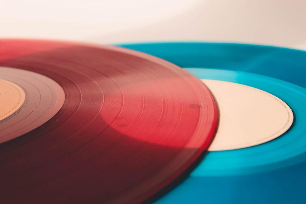 Two vinyl records, one red and one blue, both with a see-through design.